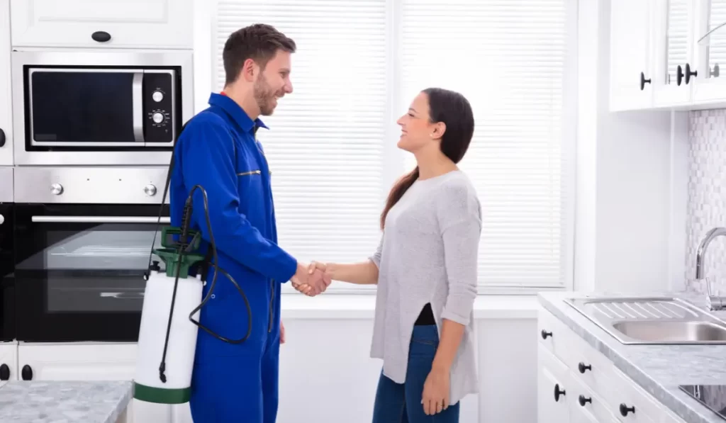 Smiling Woman Showing Thumbs Up Sign With Pest Control Worker