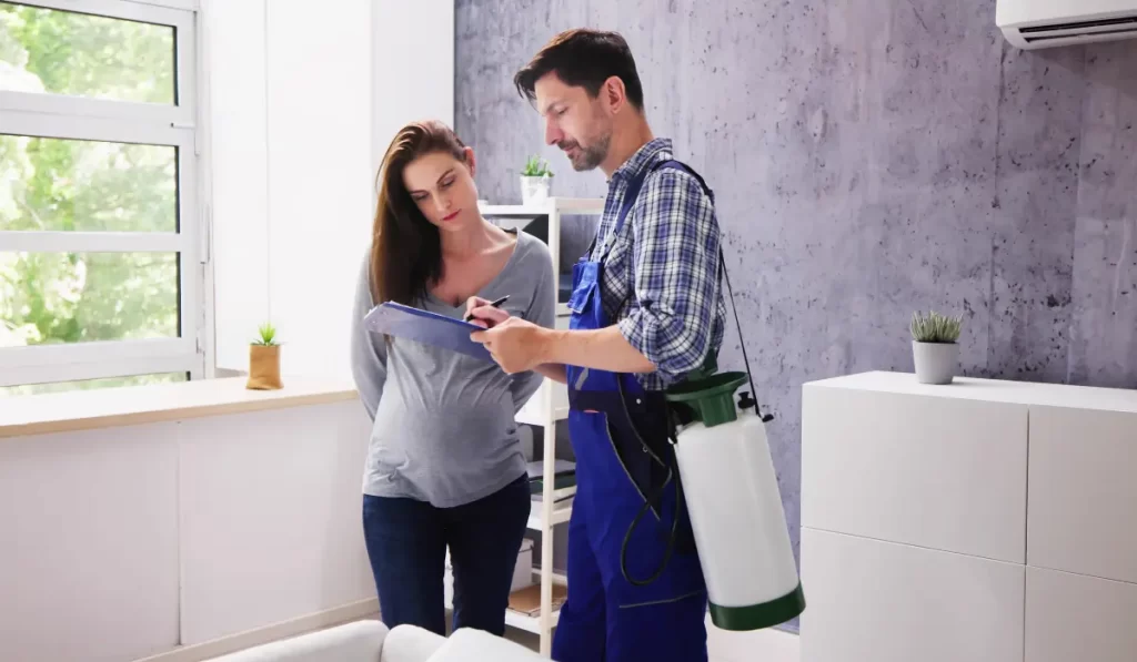 Young Male Pest Control Worker Showing Invoice To Woman